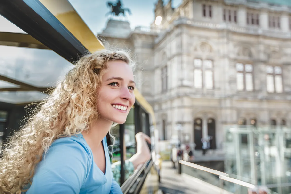 Junge Frau mit Locken lächelt vor der Wiener Staatsoper