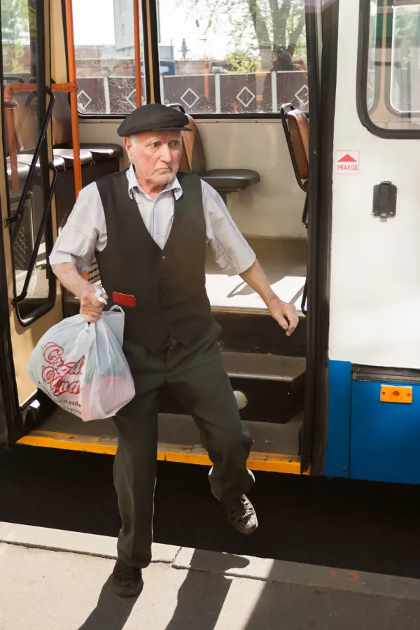 Älterer Mann mit Einkaufstasche steigt aus einem Bus